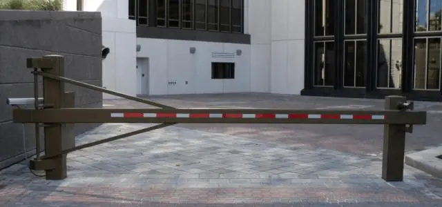 A brown metal security gate with red reflectors blocks a paved entryway to a building.