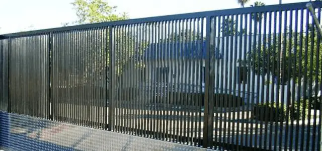 Sliding security gate with slim vertical bars allowing limited visibility through.