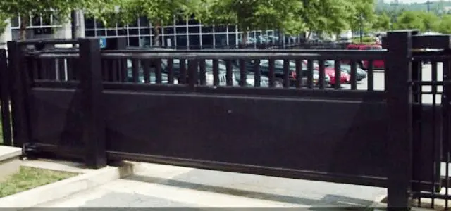 A sturdy black sliding security gate blocks the entrance to a parking lot.