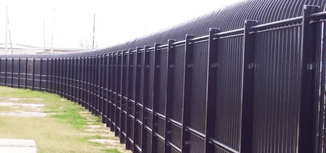 Curved metal fence with closely spaced black slats, offering perimeter security.