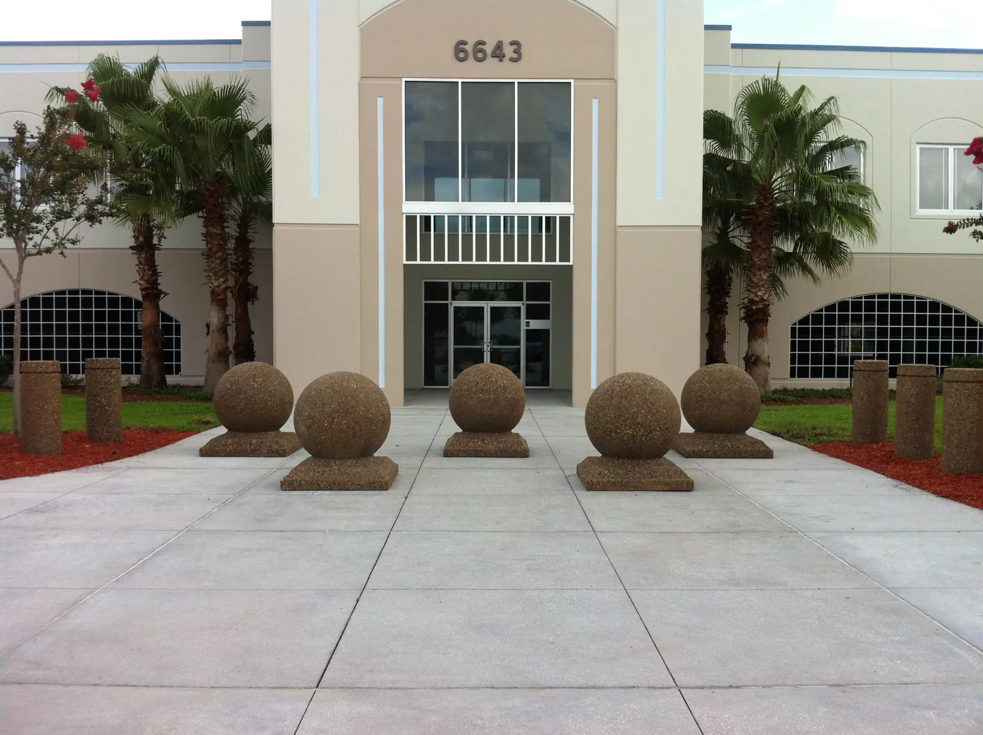 Stone spheres serve as decorative bollards along the path leading to a building's entrance.