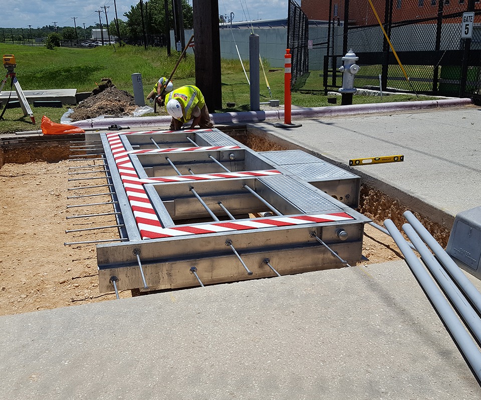 Installation of a striped vehicle barrier with steel reinforcements at an outdoor facility.