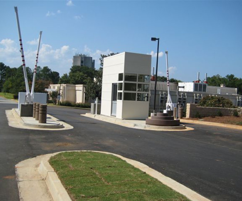 Guard booth with raised barrier arms at a gated entry checkpoint.