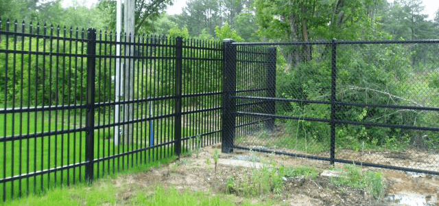 Black metal fence with integrated chain-link section and a closed gate.