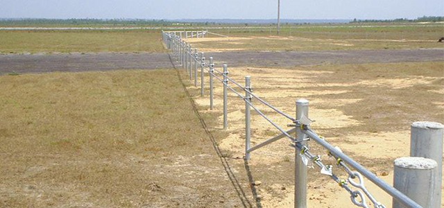 Low metal chain barrier stretching across a dry field with spaced-out posts.