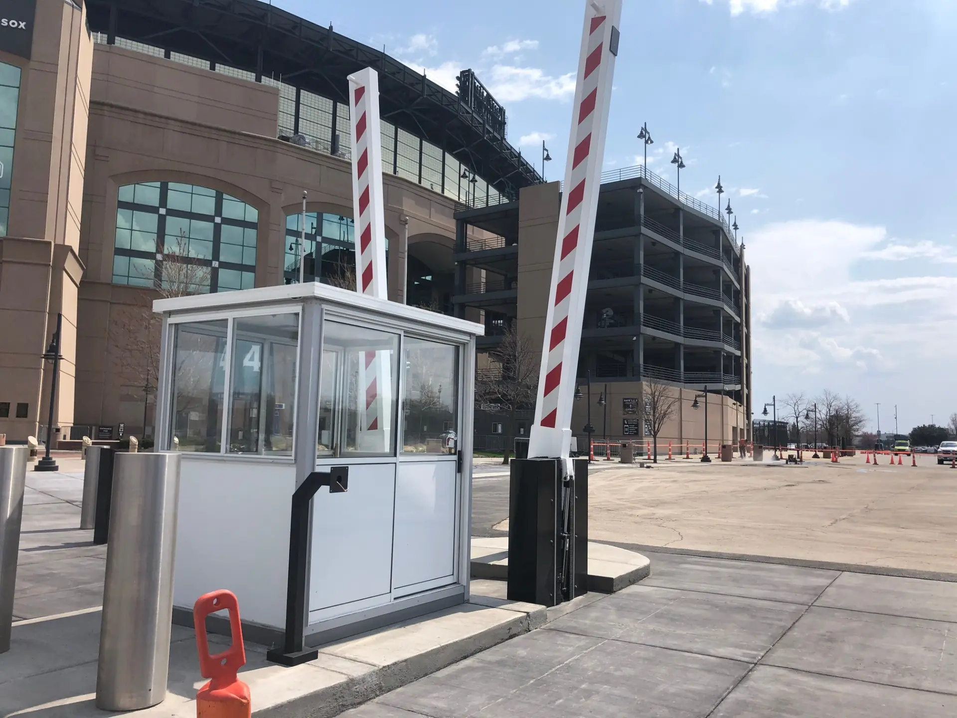 White security booth with two raised striped barrier arms in front of a stadium entrance.