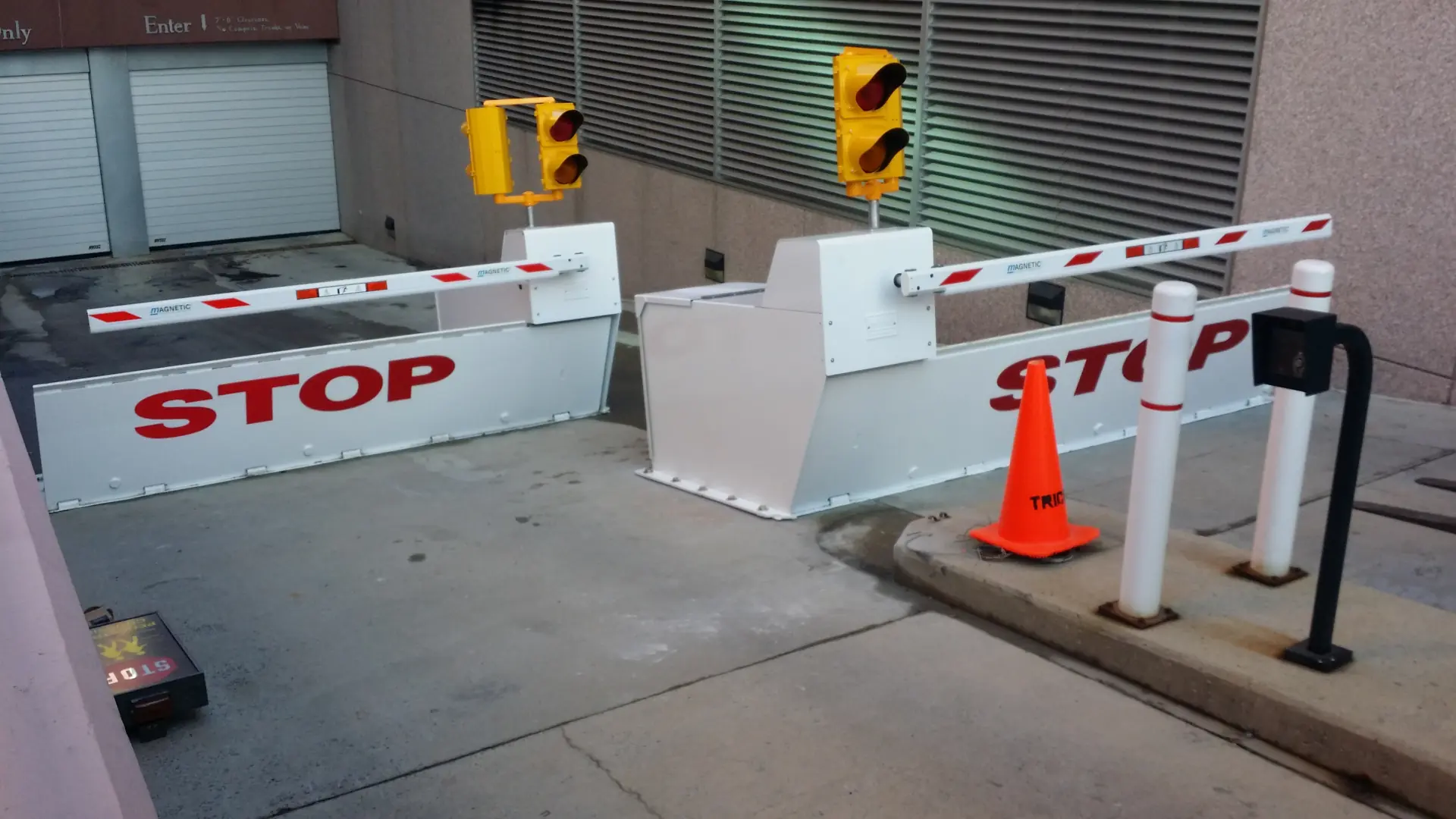 Crash-rated white barriers with red letters and traffic control arms guard a restricted-access area.