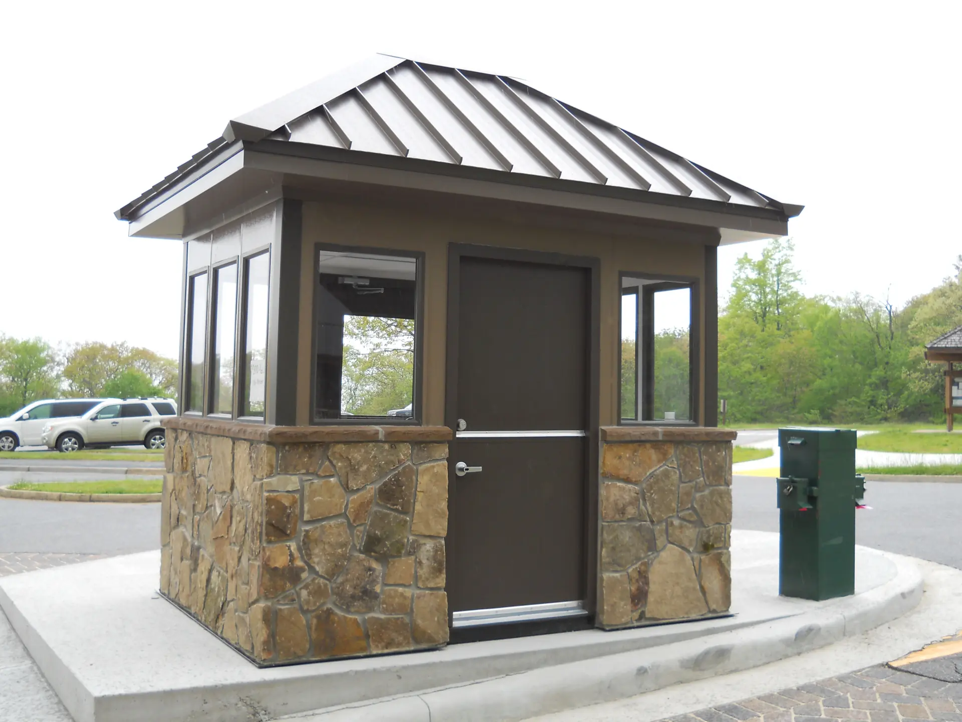 Rustic-style guard booth with stone details and a dark brown door.