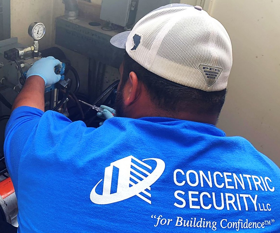 Worker in blue uniform operates tools to repair a pressurized hydraulic system.