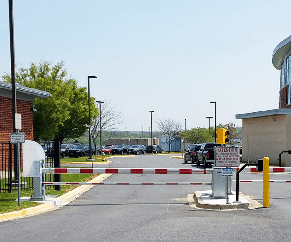 A red-and-white barrier gate blocks a road near a security checkpoint.