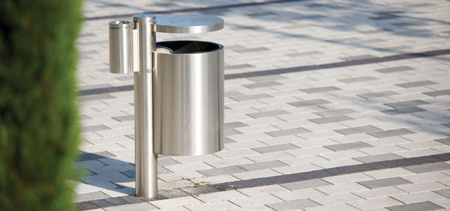Modern trash bin with a metallic finish placed on a clean, paved pedestrian area.