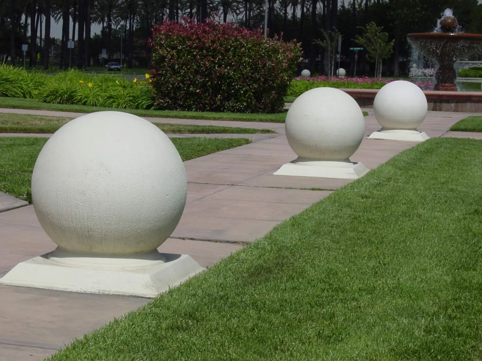White spherical bollards line a pathway in a landscaped park.
